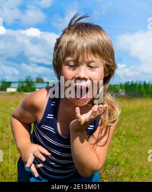 Emotionen des Kindes. Der Junge tanzt. Gesichtsausdruck fröhlich glücklich. Hände in Bewegung. Stockfoto