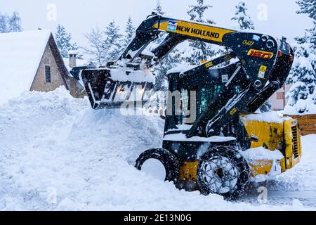 Auron, Frankreich 01.01.2021 EIN Ernteschlepper reinigt Schnee in einem Skigebiet auf der Straße bei starkem Schneefall. Bergdorf. Hochwertige Fotos Stockfoto