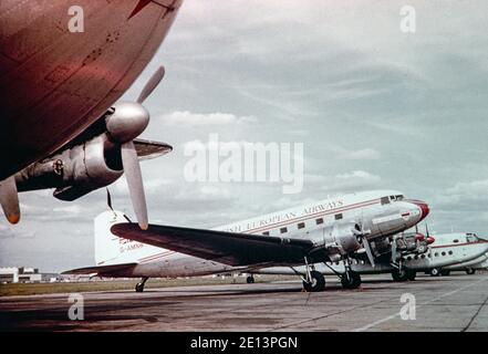 Ein Vintage-Farbfoto aus den späten 1950er Jahren ein British European Airways, BEA, Douglas DC-3, Registrierung G-AMNW, geparkt am Flughafen London Heathrow in England. Dahinter ist ein Dan Air Avro York zu sehen. Stockfoto