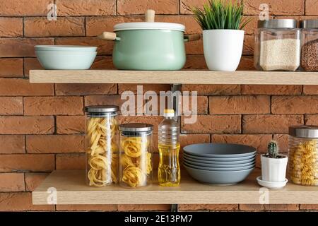 Set von Utensilien und Gläser mit Produkten auf Küchenregalen Stockfoto