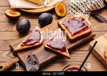 Brotscheiben mit köstlicher hausgemachter Pflaumenmarmelade auf Holz Hintergrund Stockfoto