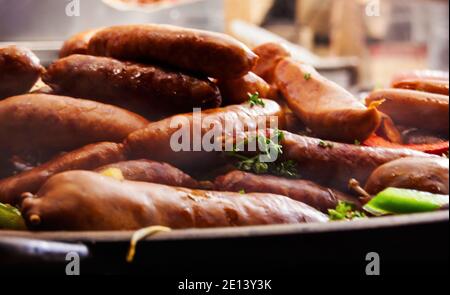 Heiß geschmorte traditionelle Wurst mit Gemüse in großer Pfanne auf dem Straßenmarkt. Nahaufnahme. Dampf wird erhöht. Weihnachtsmarkt in Paris. Stockfoto