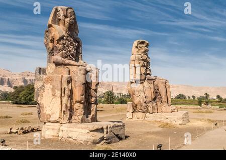 Dies ist die archäologische Stätte 1350BC an den Memnonkolossen des alten Ägyptens, nicht weit vom Nil und der Stadt Luxor, die früher als Theben bekannt war. Die Statuen sind vom Pharao Amenhotep III, es gibt zwei kleinere Statuen an seinen Füßen, eine ist seine Mutter, die andere seine Frau. Ursprünglich gebaut, um den Eingang zum Amenoteps Tempel gegen das Böse zu schützen, wurden sie auch gesehen, um das Westufer des Nils zu bewachen. Die Kolossi haben unter schweren Erdbebenschäden gelitten, aber nach 3500 Jahren stehen bleiben. Stockfoto