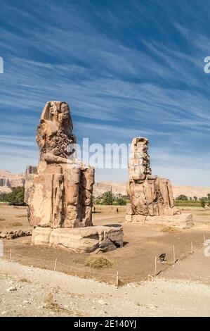 Dies ist die archäologische Stätte 1350BC an den Memnonkolossen des alten Ägyptens, nicht weit vom Nil und der Stadt Luxor, die früher als Theben bekannt war. Die Statuen sind vom Pharao Amenhotep III, es gibt zwei kleinere Statuen an seinen Füßen, eine ist seine Mutter, die andere seine Frau. Ursprünglich gebaut, um den Eingang zum Amenoteps Tempel gegen das Böse zu schützen, wurden sie auch gesehen, um das Westufer des Nils zu bewachen. Die Kolossi haben unter schweren Erdbebenschäden gelitten, aber nach 3500 Jahren stehen bleiben. Stockfoto