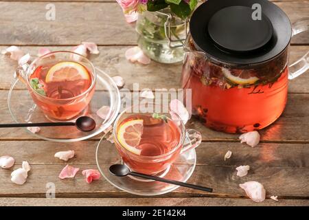 Teekanne und Tassen mit floralem Tee auf Holzhintergrund Stockfoto