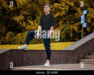 Schwarze Casual T-Shirt Mockup auf Kerl stehen vor verschwommenem Hintergrund im Park. Urban Style Kleidungsvorlage Nahaufnahme, stilvolle Branded Kleidung, für p Stockfoto