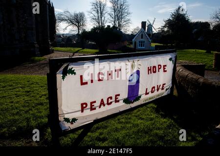 Thaxted Essex England UK Januar 2021 Thaxted Kirche und Licht, Hoffnung, Frieden, Liebe Zeichen mit Alms House im Hintergrund Stockfoto