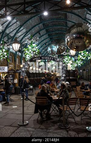 Weihnachtskäufer sitzen und nehmen sich einen gesellschaftlich distanzierten Kaffee in der Covent Garden Piazza während der Tier2 Coronavirus Lockdown Measures, London UK Stockfoto