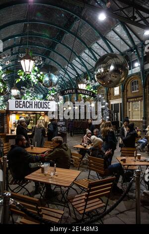 Weihnachtskäufer sitzen und nehmen sich einen gesellschaftlich distanzierten Kaffee in der Covent Garden Piazza während der Tier2 Coronavirus Lockdown Measures, London UK Stockfoto