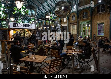 Weihnachtskäufer sitzen und nehmen sich einen gesellschaftlich distanzierten Kaffee in der Covent Garden Piazza während der Tier2 Coronavirus Lockdown Measures, London UK Stockfoto