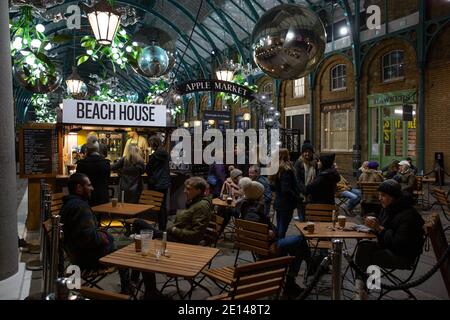 Weihnachtskäufer sitzen und nehmen sich einen gesellschaftlich distanzierten Kaffee in der Covent Garden Piazza während der Tier2 Coronavirus Lockdown Measures, London UK Stockfoto