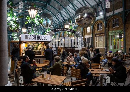 Weihnachtskäufer sitzen und nehmen sich einen gesellschaftlich distanzierten Kaffee in der Covent Garden Piazza während der Tier2 Coronavirus Lockdown Measures, London UK Stockfoto