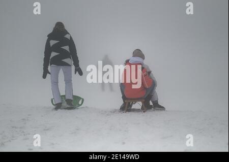 Hellenthal, Deutschland. Januar 2021. Besucher Rodeln im dichten Nebel auf einer Piste im Skigebiet 'Weißer Stein' in der Eifel. Nach großen Menschenmengen am Wochenende hat die Gemeinde Hellenthal die Parkplätze gesperrt. Quelle: Henning Kaiser/dpa/Alamy Live News Stockfoto