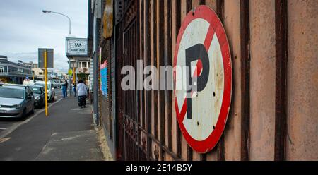 Woodstock- Cape Town, South Africa - 14/11/2020 Rusty 'No Parking' Schild an einem Tor auf der Albert Road. Menschen und fließender Verkehr im Hintergrund. Stockfoto