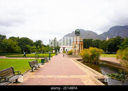 Gärten - Kapstadt, Südafrika - 23/11/2020 Gärten an einem bewölkten Tag. Pferdestatue, Grün und wolkenbedeckten Berg. Mann in Gesichtsmaske, der vorbei geht Stockfoto