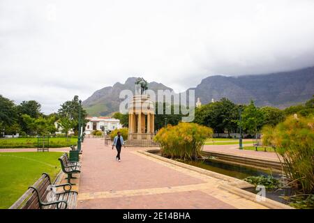 Gärten - Kapstadt, Südafrika - 23/11/2020 Gärten an einem bewölkten Tag. Pferdestatue, Grün und wolkenbedeckten Berg. Mann in Gesichtsmaske, der vorbei geht Stockfoto