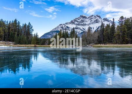 Johnson Lake gefrorene Wasseroberfläche im Winter. Schneebedeckter Cascade Mountain im Hintergrund. Banff National Park, Kanadische Rockies, Alberta, Kanada. Stockfoto