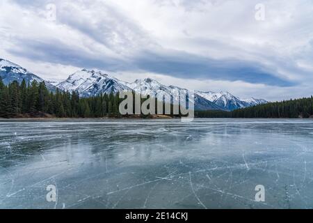 Johnson Lake gefrorene Wasseroberfläche im Winter. Schneebedeckter Berg im Hintergrund. Banff National Park, Kanadische Rockies, Alberta, Kanada. Stockfoto