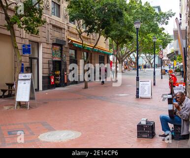 Kapstadt, Südafrika - 23/11/2020 ruhiger Marktplatz, Mann bukking mit Gitarre im Vordergrund. Stockfoto