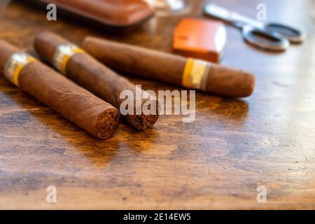 Zigarren und Accessoires auf einem Schreibtisch aus Holz, Nahaufnahme. Kubanische Qualität Zigarre Tabak Rauchen Luxus Lebensstil. Stockfoto