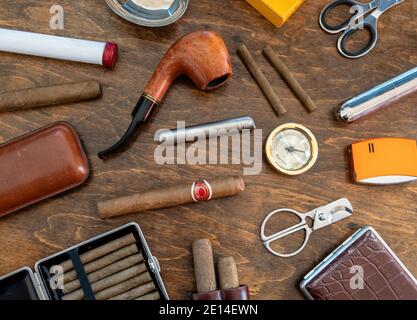 Raucherset Zubehör. Zigarren, Pfeifen, Zigarillos und Zigaretten, Cutter, Feuerzeuge, Etuis auf einem Holztisch Hintergrund. Kubanische Qualitätsmarke Zigarren, l Stockfoto