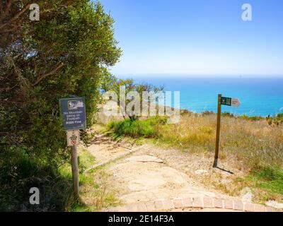 Signal Hill - Kapstadt, Südafrika - 02/12/2020 Wanderweg auf Signal Hill. Üppiges Grün im Vordergrund und blaues Meer im Hintergrund. Stockfoto