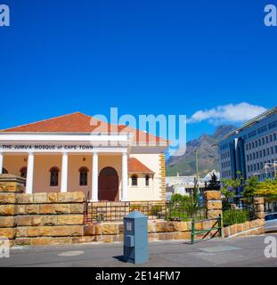 Kapstadt, Südafrika - 02/12/2020 das Jumu'a Moschee Gebäude in Kapstadt. Langes quadratisches Gebäude, Berg und blauer Himmel im Hintergrund. Stockfoto