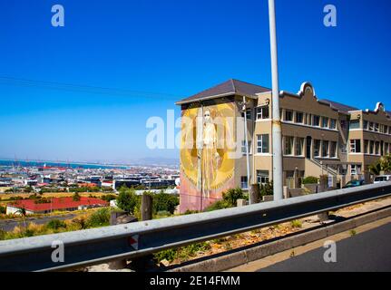 Cape Town, South Africa - 02/12/2020 Road view of Building with female empowerment mural painted on it. Farbenfrohe Kapstadt im Hintergrund. Stockfoto