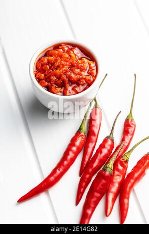 Rote Chili-Paste und Chili-Pfeffer auf weißem Tisch. Stockfoto