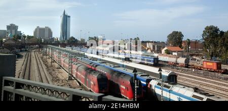 Schienenpersonenwagen, die in einer Transporteisenbahn in der Stadt Haifa, Israel, untätig sitzen. Das Sail Tower Gebäude ist im Hintergrund. Stockfoto