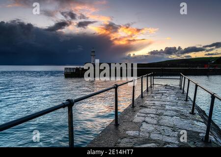 Sonnenaufgang und ein Leuchtturm im Hafen von Mevagissey, Cornwall Stockfoto