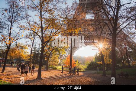 Paris, Frankreich - Oktober 31 2015: Touristen, Einheimische und Familien genießen einen malerischen Herbstspaziergang, während das Sonnenlicht durch den berühmten Eiffelturm in Pari bricht Stockfoto