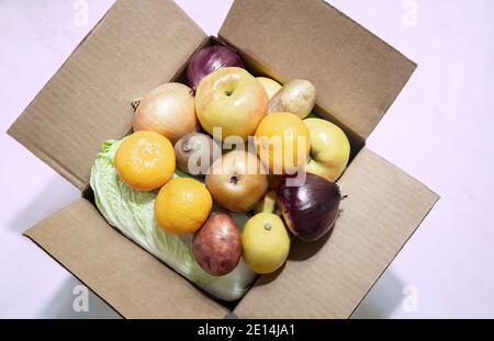 Der Karton enthält eine Vielzahl von Obst und Gemüse. Umweltfreundliche Verpackung. Nahrungsmittellieferung während der Coronavirus-Pandemie. Draufsicht, Kopieren en Stockfoto