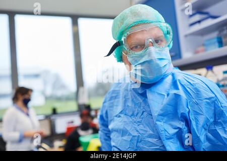 Mann in Schutzkleidung arbeitet mit Covid-19-Impfstoff in der Labor eines Biotechnologieunternehmens Stockfoto