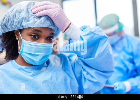 Erschöpfter Arzt in Schutzkleidung mit Burnout in der Klinik während Covid-19 Pandemie Stockfoto