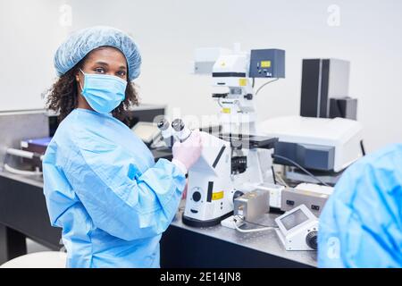 Afrikanische Frau als Forscherin arbeitet am Mikroskop in Ein Labor mit Covid-19-Impfstoff gegen eine Coronavirus-Pandemie Stockfoto