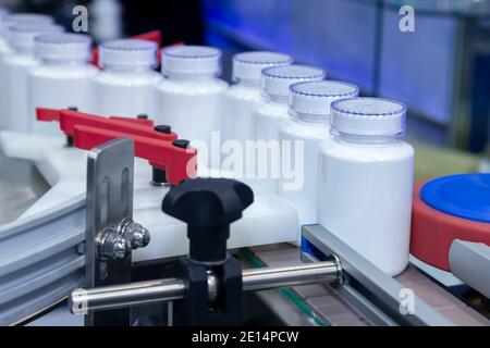 Weiße Medizin Plastikflasche auf Produktionslinie des Förderers an der Abfüllmaschine in der medizinischen Fabrik. Selektiver Fokus. Pharmazeutische Herstellung und Stockfoto