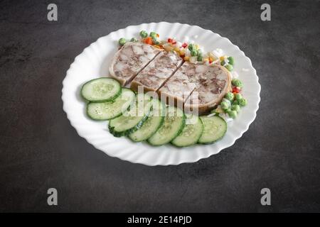 Auf dem Tisch auf einem Teller mit köstlichen Fleisch Vorspeise: Gefüllt mit Fleisch und Speck Schweinefleisch Magen, in Scheiben geschnitten, neben Gemüse und frischen Gurken. Schließen-U Stockfoto
