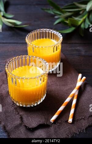 Frisch gebackene Orangensaft wunderschön in zwei Gläsern auf einem Holztisch angeordnet, Draufsicht, Portrait, Stockfoto