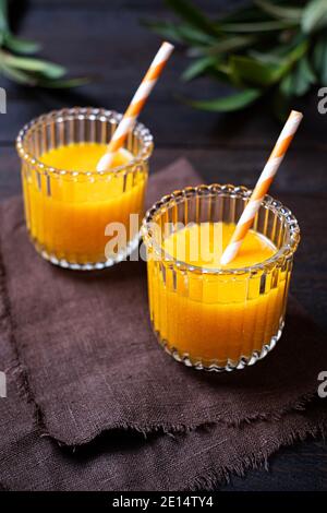 Frisch gebackene Orangensaft wunderschön in zwei Gläsern auf einem Holztisch angeordnet, Draufsicht, Portrait, Stockfoto