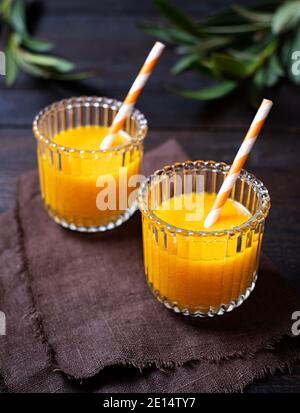 Frisch gebackene Orangensaft wunderschön in zwei Gläsern auf einem Holztisch angeordnet, Draufsicht, Portrait, Stockfoto