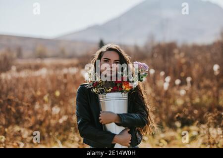 Frau hält einen hohen Eisenkeimer mit Blumen in der Open Air in der Natur Stockfoto