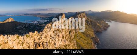 Luftpanorama entlang steiler Lifs des Kap Formentor bei Sonnenuntergang, mit Port de Pollença und Cala Sant Vicenç im Hintergrund, Mallorca, Balearen Isla Stockfoto