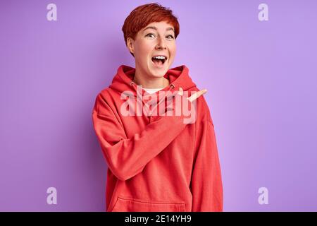 Frau in Casual tragen zeigt Finger an der Seite, Foto für Werbung. Glückliche Frau zeigt auf etwas Stockfoto