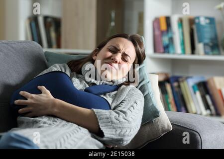 Frau leidet Schmerzen mit gebrochenem Arm in einer Schlinge liegend Auf einer Couch zu Hause Stockfoto