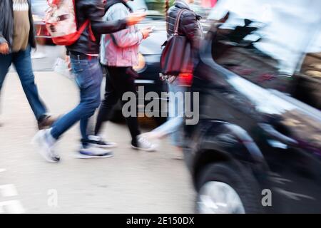 Bild mit Kamera gemacht Bewegungsunschärfe-Effekt von Menschen überqueren Eine Straße zwischen Autos Stockfoto