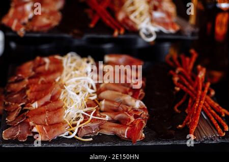 Antipasti Platte kaltes Fleisch, Schinken, Scheiben Schinken, Rindfleisch ruckig, Salami und Käse Platte auf grauem Hintergrund. Nahaufnahme von Bier Snacks Set Stockfoto