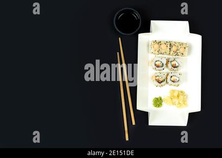 Japanisches Sushi-Set zum Mitnehmen mit Essstäbchen und Sojasauce auf dunklem Hintergrund, Nahaufnahme, Kopierbereich Stockfoto