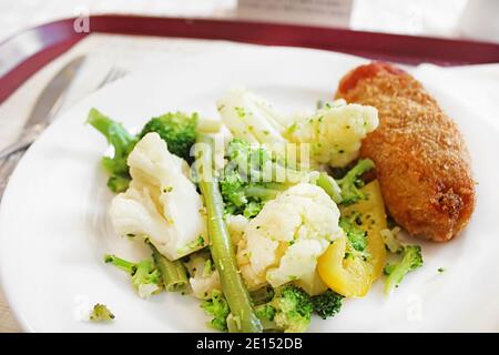 Mittagessen mit Kiewer Koteletts, Brokkoli, Blumenkohl und Spargel auf dem weißen Teller Stockfoto