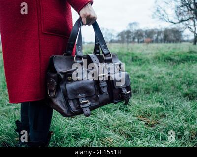 Frau in rotem Mantel mit einer Designer-Leder-Handtasche Stockfoto
